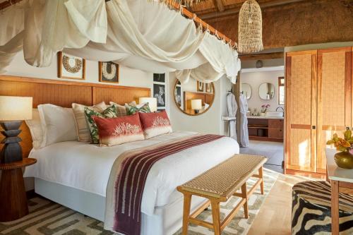 a bedroom with a large bed and a bathroom at Taj Bush Lodge in Hoedspruit