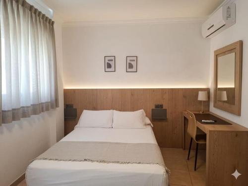 a bedroom with a bed and a desk with a mirror at Apartamentos El Barrio in Nerja