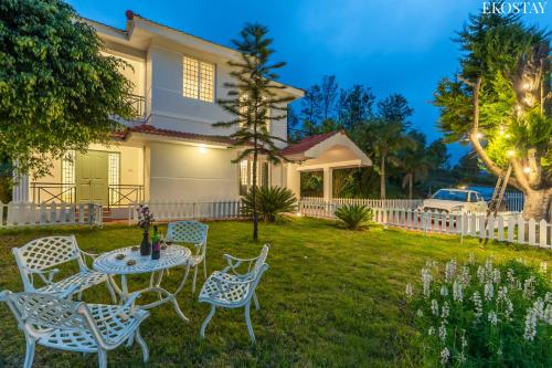 a patio with chairs and a table in front of a house at EKOSTAY - Villa Eve in Ooty