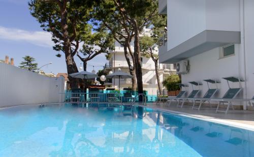 a swimming pool with chairs and umbrellas next to a building at Residence Dolce Vita in San Benedetto del Tronto
