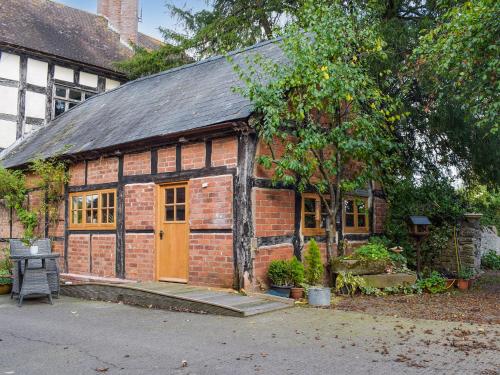 a brick building with a door and a tree at Gardeners Cottage in Putley