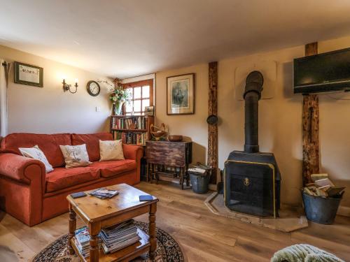 a living room with a red couch and a wood stove at The Old Tack Room - Uk49233 in Tilshead