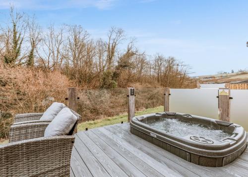 a hot tub on a wooden deck with a couch at The Astbury Golf And Lodge Resort in Bridgnorth