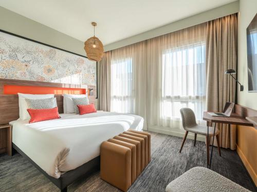 a hotel room with a large bed and a desk at Mercure Achères St Germain en Laye in Achères