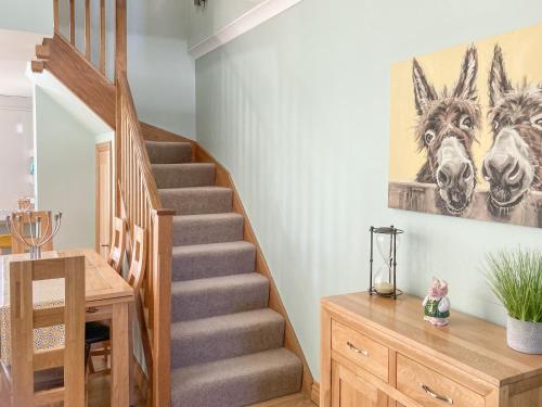 a staircase in a home with a painting of horses on the wall at Ardstinchar Mews in Ballantrae