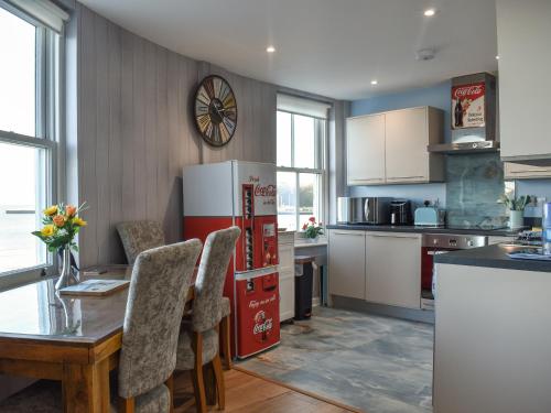 a kitchen with a table and a refrigerator at Seagulls Lookout in Weymouth