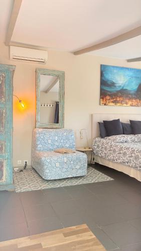 a bedroom with a bed and a chair and a mirror at La Villa D’Aimée in Vidauban