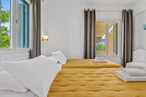 a bedroom with two beds and two windows at Kamelia Hotel in Spetses