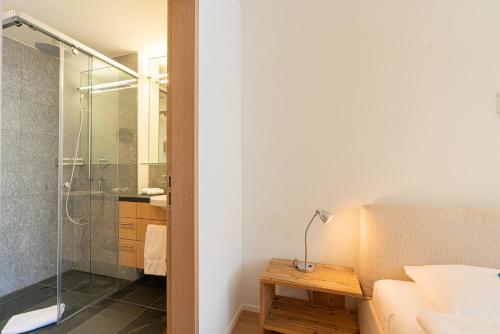 a bathroom with a shower and a bed and a table at Residenza Edelweiss 5 3 in Sils Maria