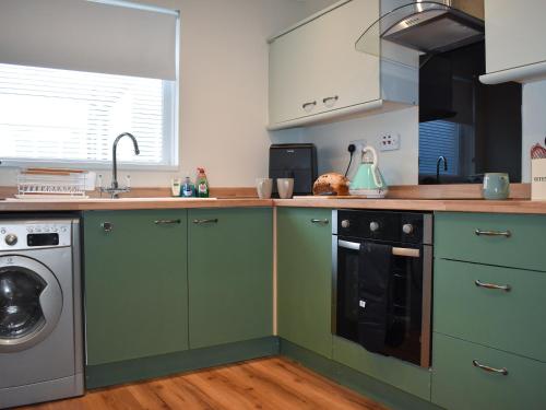 a kitchen with green cabinets and a washing machine at Marina Views in Amble
