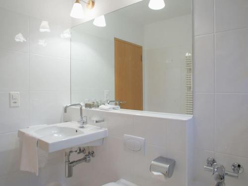 a white bathroom with a sink and a mirror at Residenza Alpenrose 22 in Sils Maria