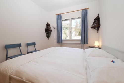 a white bedroom with a large white bed and a window at Residenza Alpenrose 22 in Sils Maria