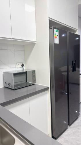a kitchen with a stainless steel refrigerator and white cabinets at The Captains Suite in Gaborone