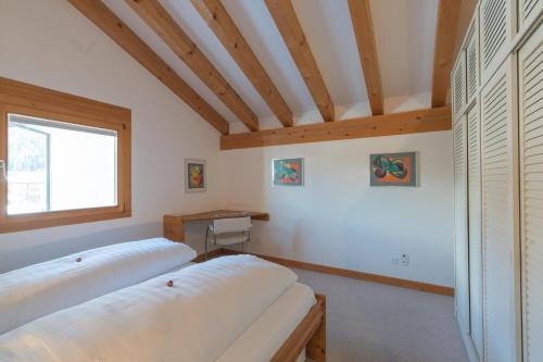 two beds in a room with a window and wooden ceilings at Chesa Cravunera 29 in Sils Maria