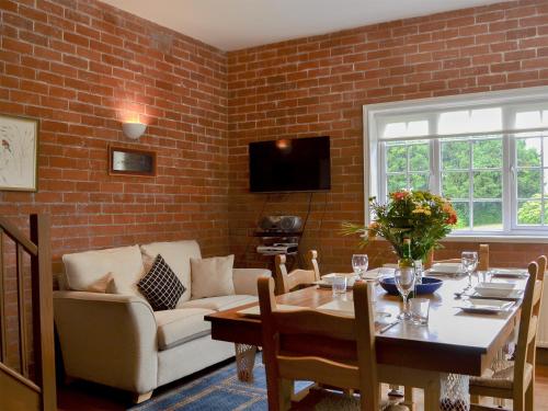 a living room with a table and a brick wall at The Stables in Eardisland