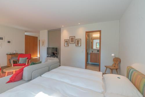 a bedroom with a white bed and a living room at Chesa Piol Studio in Maloja