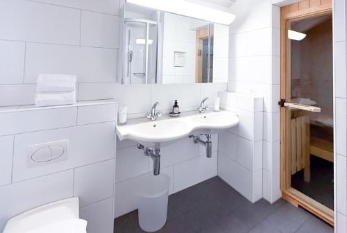 a white bathroom with two sinks and a mirror at Residenza Alpenrose 61 in Sils Maria