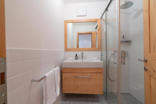 a bathroom with a sink and a shower with a mirror at Chesa Blaunca B4 in Maloja