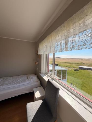 a bedroom with a bed and a window and a chair at Vagnsstadir Hostel in Borgarhöfn