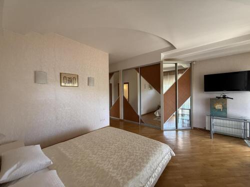 a bedroom with a bed and a flat screen tv at Дом в Аркадии - море рядом! in Odesa