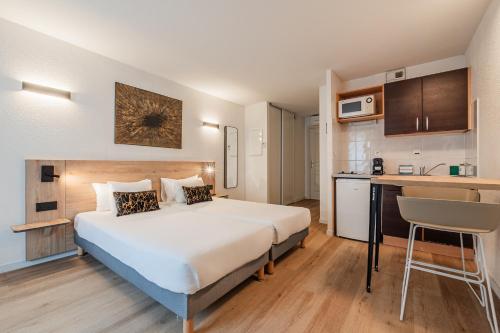 a hotel room with a large bed and a kitchen at Residhotel Mulhouse Centre in Mulhouse