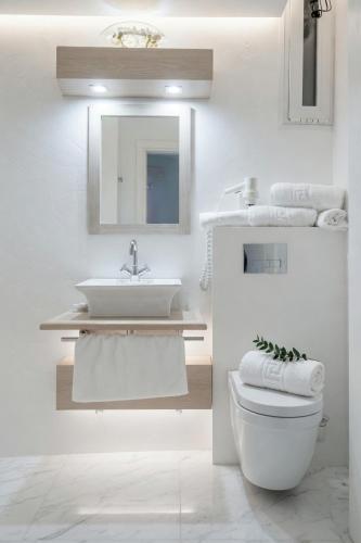 a white bathroom with a sink and a toilet at Hotel Rex in Kalabaka