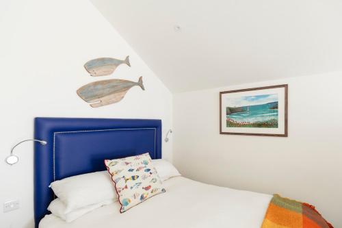 a bedroom with a white bed with a blue headboard at Beach Hut Suites in Bognor Regis
