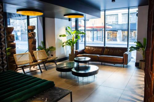 a lobby with a couch and tables and windows at Almacruz Hotel y Centro de Convenciones (Ex Galerías) in Santiago