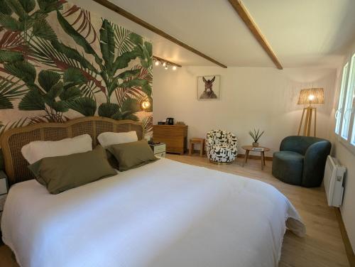 a bedroom with a large white bed and a blue chair at l'Orée du Bois in Saint-Brice