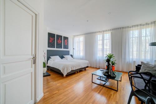 a white bedroom with a bed and a living room at Le Limas in Avignon