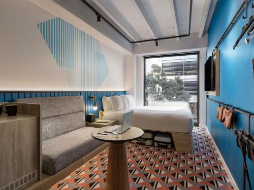a bedroom with a bed and a couch and a table at TRIBE Auckland in Auckland