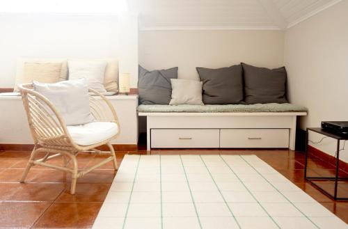 a bench with pillows and a chair in a room at Old Town Apt with Ocean Views in Sesimbra