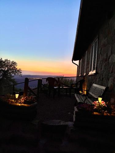 a sunset view of a house with a table and chairs at Agriturismo Colle Sereno in Castiglione dʼOrcia