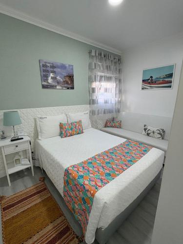 a small bedroom with a bed and a night stand at Moradia Ricardo - Nazaré in Nazaré