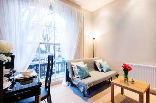 a living room with a chair and a table and a window at Elicia's South Kensington Apartment in London