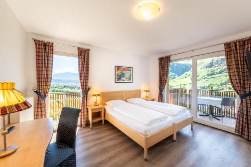 a bedroom with a bed and a table and a balcony at Hotel Hanny Panoramic Views over Bolzano in Bolzano