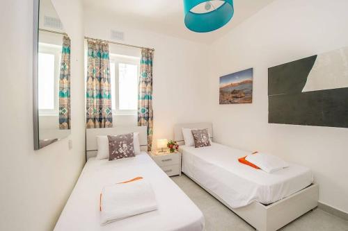 a bedroom with two beds and a mirror at Hillock Residence Marsalforn in Marsalforn
