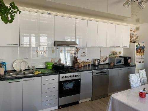 a kitchen with stainless steel appliances and white cabinets at Guest House Eltin in Bokonbayevo