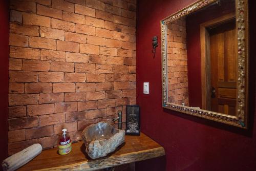 a bathroom with a brick wall and a mirror at Chalé das Flores in Brumadinho