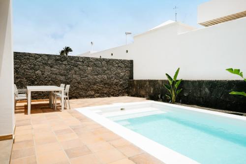 a patio with a swimming pool and a table at Villa Volcano by CasasBlancas in Yaiza