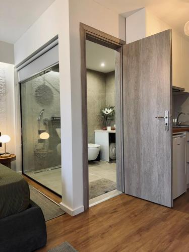 a bathroom with a glass door leading to a bathroom with a toilet at Apellou Apartments in Vathý
