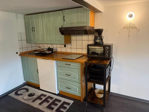 a kitchen with green cabinets and a microwave at Ferienwohnung Mutzelmann in Kurort Gohrisch