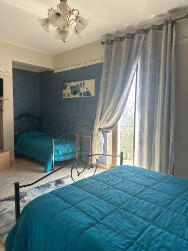 a bedroom with a blue bed and a window at Colledisisto Guest House & Restaurant in Pomarico