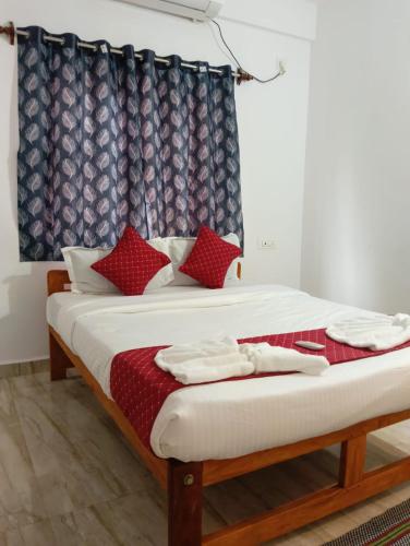 a bedroom with a large bed with red and white pillows at Ojasvi Experience in Morjim