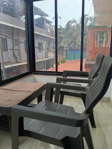 two chairs and a table in front of a window at Ojasvi Experience in Morjim