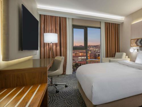 a hotel room with a bed and a desk and a window at Mercure Ankara Kızılay in Ankara