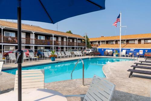 a pool in front of a hotel with chairs and an umbrella at The Janmere Motel in Hampton