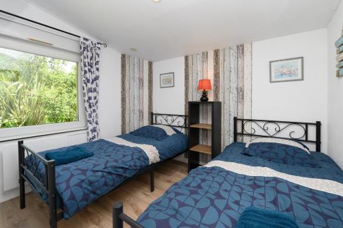 two beds in a room with a window at Domaine des légendes in Plumelin