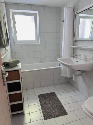 a white bathroom with a tub and a sink at Chalet Vallese Valbella Lenzerheide, great view in Valbella