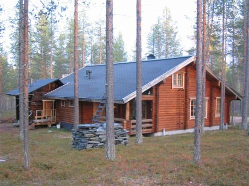 a log cabin with a black roof in the woods at Kuulapää Chalet in Äkäslompolo